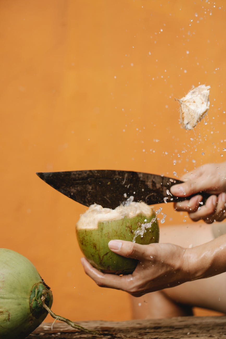 crop person cutting coconut with knife