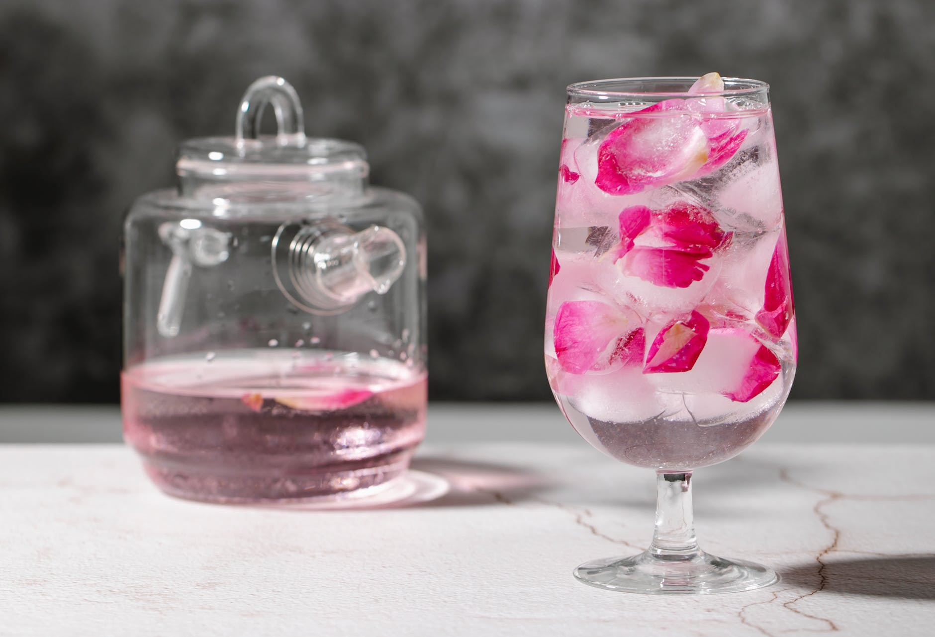 glass of drink with rose petals near jar
