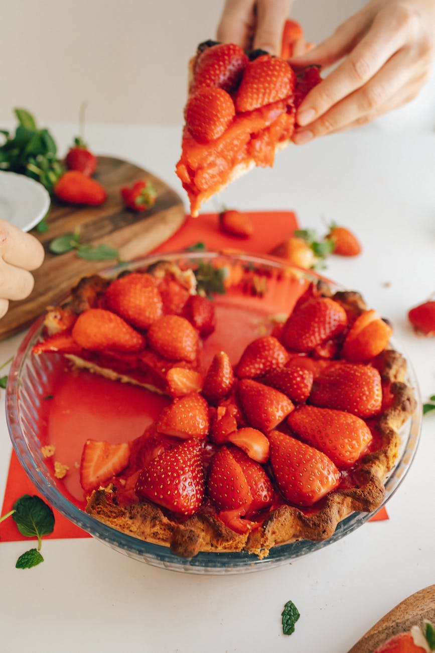 close up of a person putting a slice of strawberry pie on another persons plate