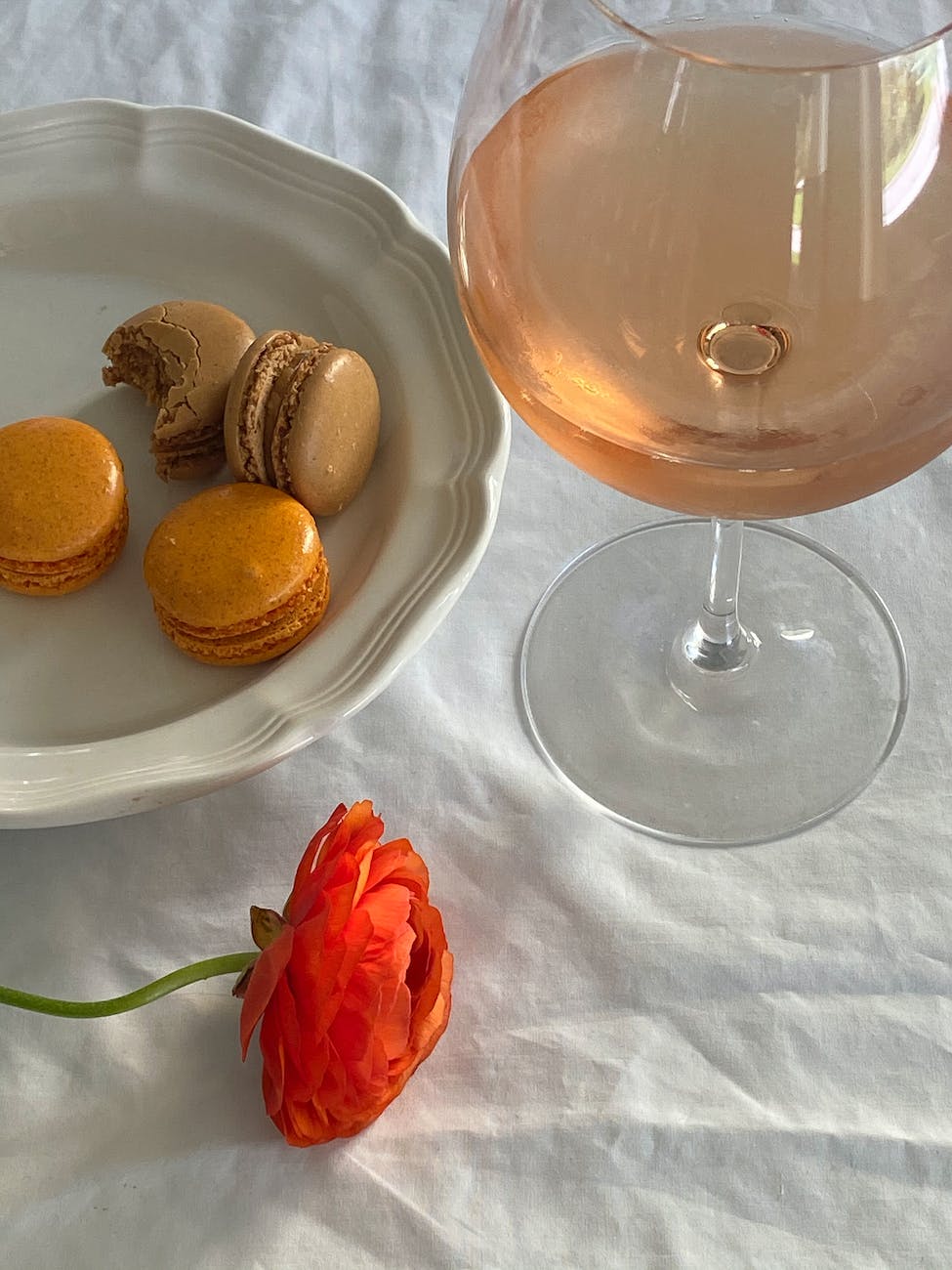glass of rose wine placed near sweet macaron