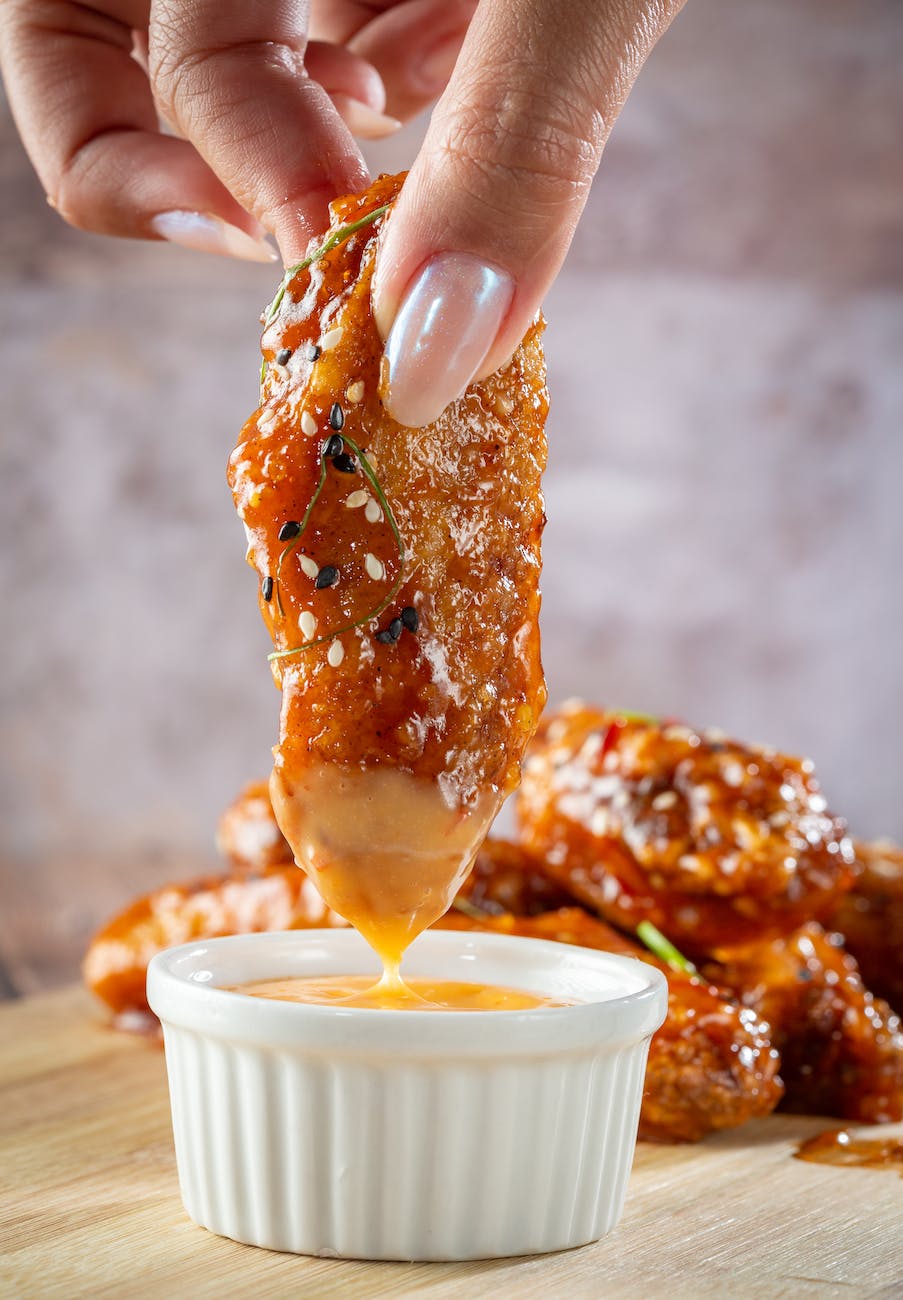 a dish of glazed chicken wings with a dip