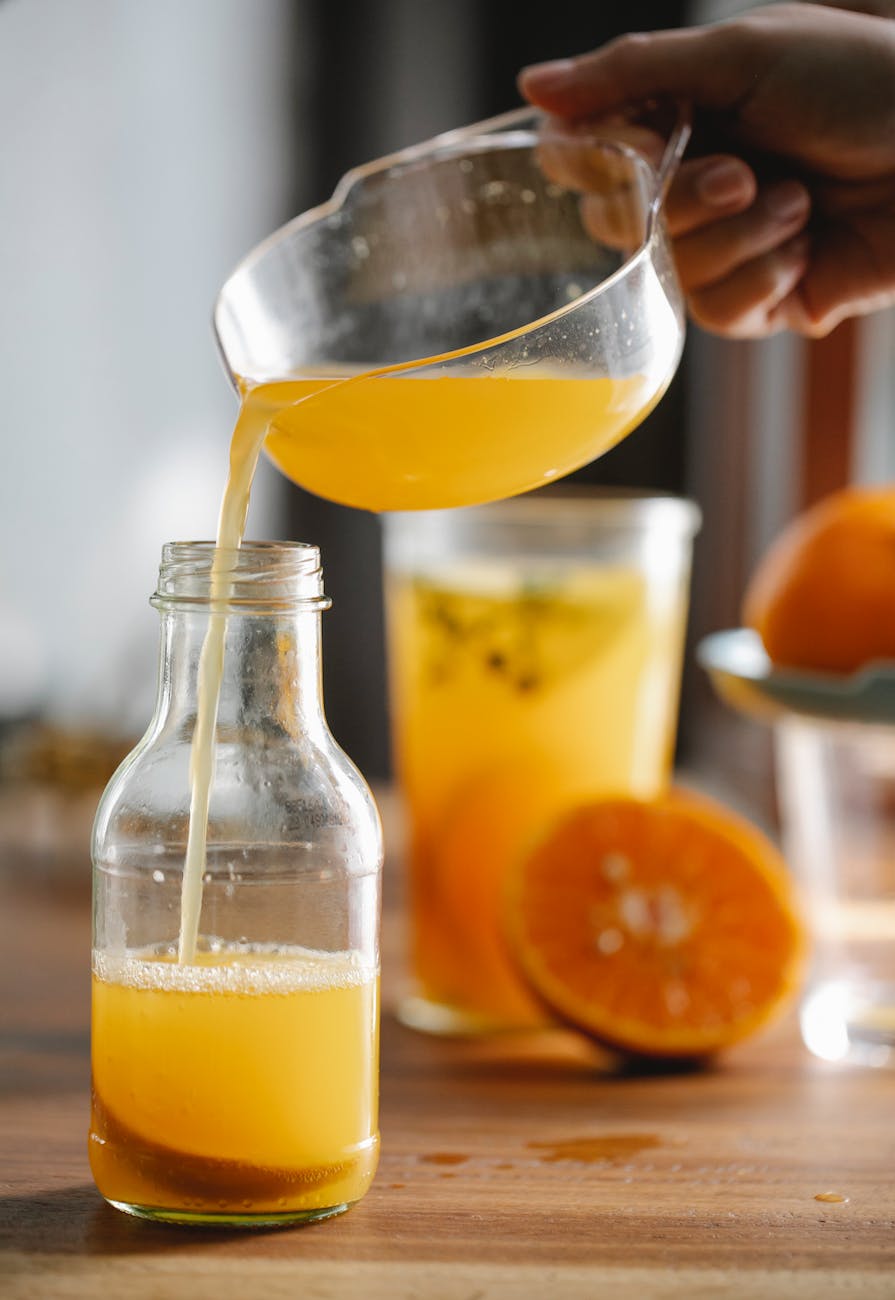 crop person pouring fresh orange juice