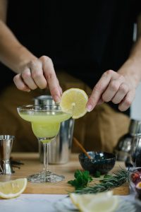person hanging slice of lemon on cocktail glass