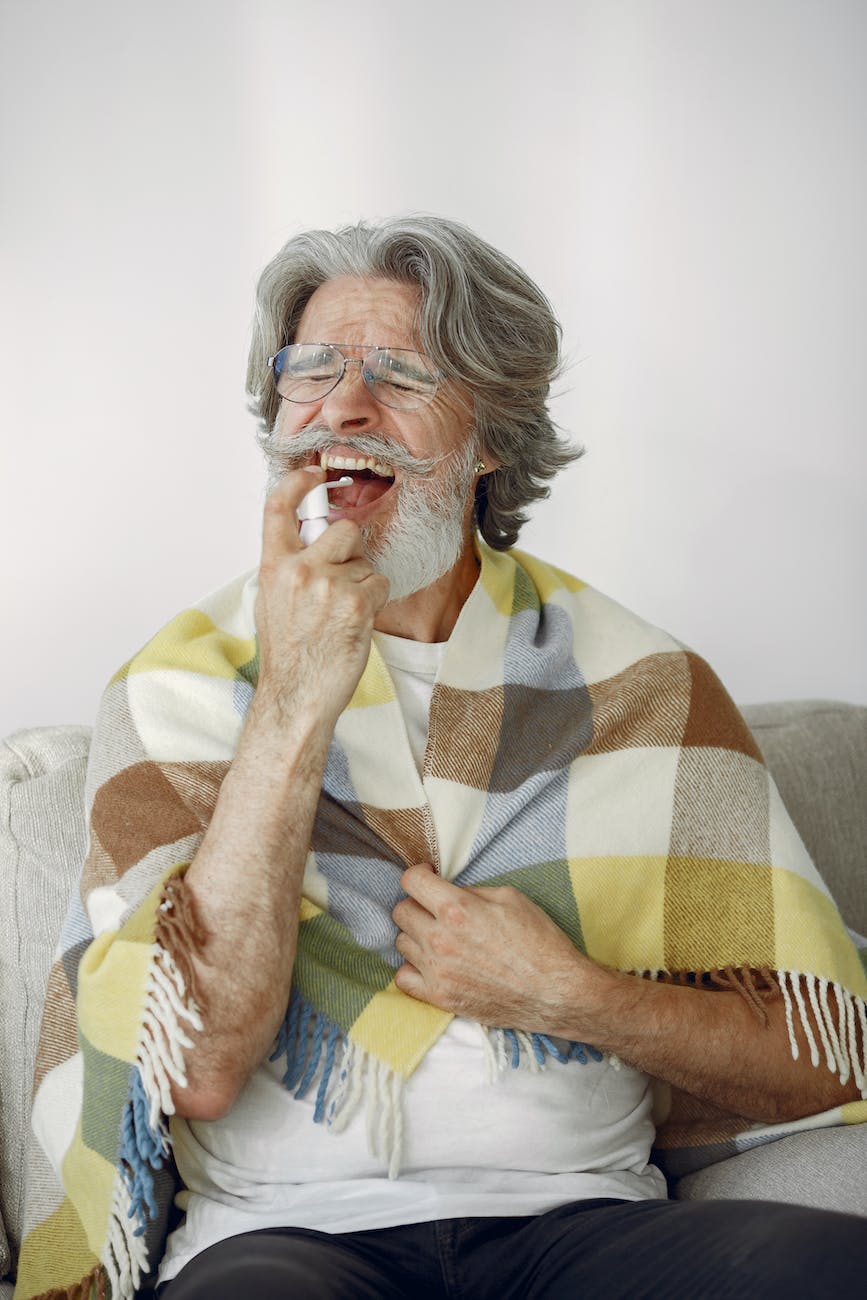 sick elderly man spraying throat