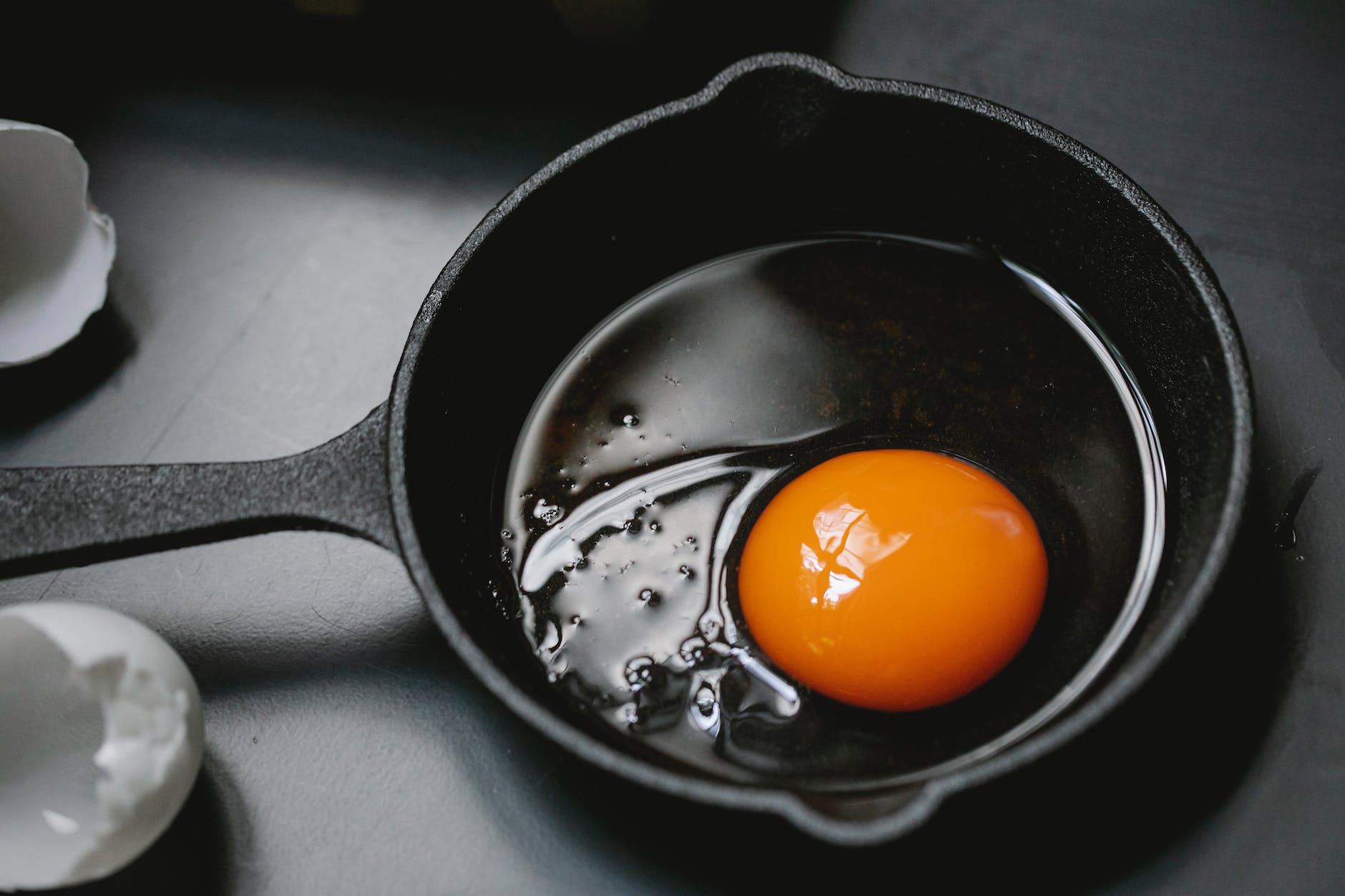 raw broken egg in frying pan placed on table