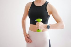 woman in black tank top holding green dumbbell