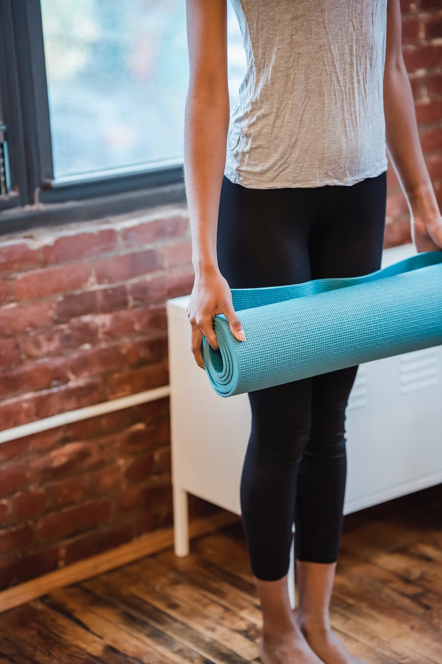 person standing with yoga mat in studio